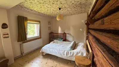 a bedroom with a bed and a wooden floor at Chatka na Lipowych Wzgórzach in Marcówka