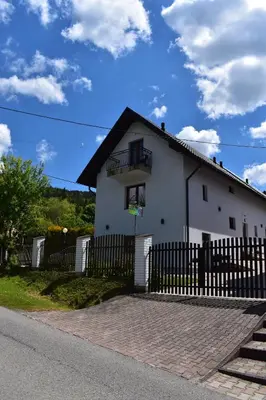 a white house with a fence in front of it at Pokoje pod Śnieżnicą in Kasina Wielka