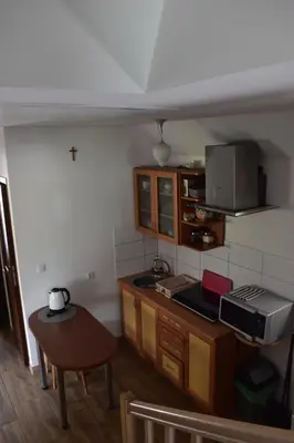 a small kitchen with wooden cabinets and a table at Pokoje pod Śnieżnicą in Kasina Wielka