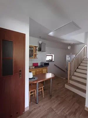 a kitchen with a table and a staircase in a room at Pokoje pod Śnieżnicą in Kasina Wielka
