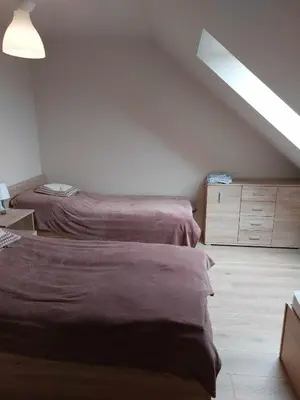 a attic bedroom with two beds and a dresser at Ważka - pokoje do wynajęcia in Targoszów