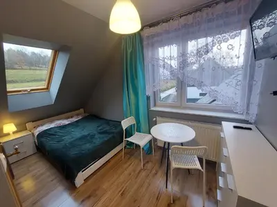 a small bedroom with a bed and a table at Ważka - pokoje do wynajęcia in Targoszów