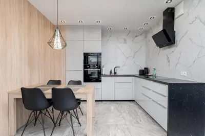 a kitchen with a wooden table and black chairs at Przedwiośnie Chic Harmony Apartment by BookingHost in Kraków