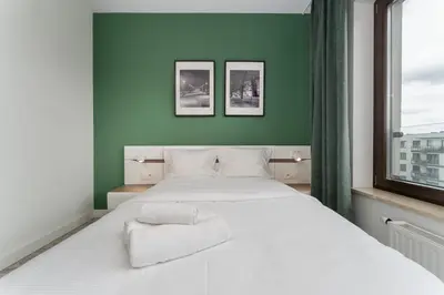 a bedroom with a white bed and a green wall at Przedwiośnie Chic Harmony Apartment by BookingHost in Kraków