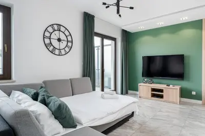 a living room with a couch and a flat screen tv at Przedwiośnie Chic Harmony Apartment by BookingHost in Kraków