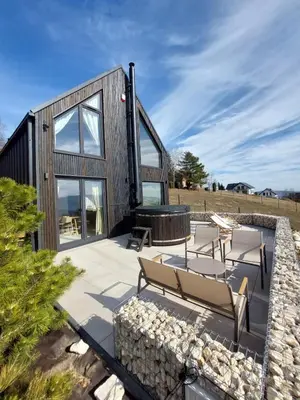 a house with a stone wall and benches on a patio at GOLaskowa in Laskowa