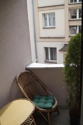 a rattan chair on a balcony with a building at Old Town Apartment Kazimierz in Kraków