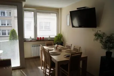a dining room table with chairs and a television on the wall at Old Town Apartment Kazimierz in Kraków