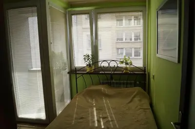 a green room with a bed in a room with windows at Old Town Apartment Kazimierz in Kraków