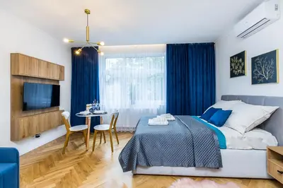 a bedroom with a bed and a table and a tv at Apartament Bonerowska Blue in Kraków