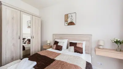 a white bedroom with a bed and a mirror at Banacha, Sun & Snow in Kraków