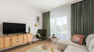 a living room with a flat screen tv on a wooden cabinet at Banacha, Sun & Snow in Kraków