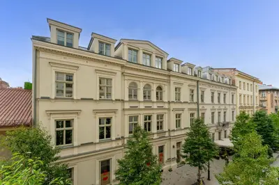 a large white building with trees in front of it at Krupnicza Apartment by VSI in Kraków