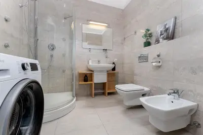 a bathroom with a toilet sink and a washing machine at Krupnicza Apartment by VSI in Kraków