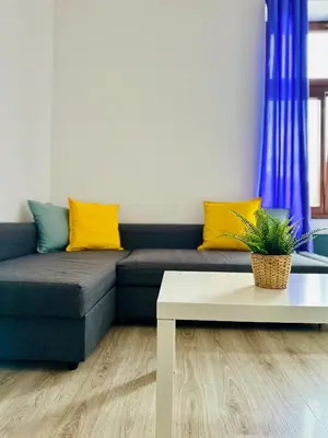 a living room with a blue couch with yellow pillows at BD KRAKOW Apart Hotel in Kraków