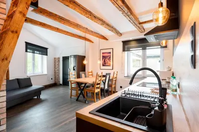 a kitchen and living room with a sink and a table at Old Town Wooden Loft Apartment by BookingHost in Kraków