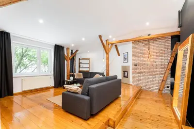 a living room with a couch and a brick wall at Old Town Wooden Loft Apartment by BookingHost in Kraków