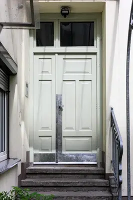 a white door on a white building with stairs at Apartament Marylin in Kraków