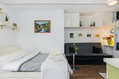 a white bedroom with a bed and a couch at Cosy Studio in Kraków