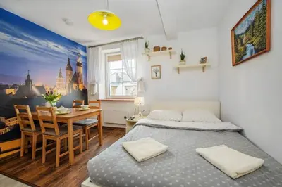 a bedroom with a bed and a dining room at Cosy Studio in Kraków