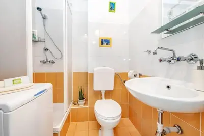 a bathroom with a white toilet and a sink at Cosy Studio in Kraków