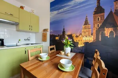 a kitchen with a table with a painting of a city at Cosy Studio in Kraków