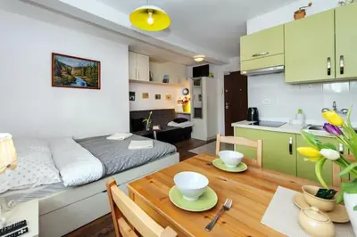 a room with a bed and a table and a kitchen at Cosy Studio in Kraków