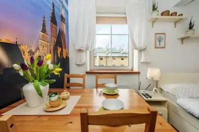 a living room with a table and a room with a bed at Cosy Studio in Kraków