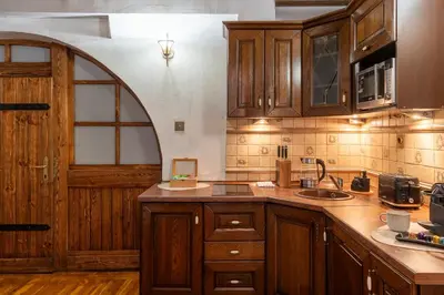 a kitchen with wooden cabinets and an archway at 500 Year House - Kraków Old Town - Historic Apartments by Staymoovers in Kraków