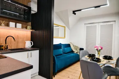 a kitchen and a living room with a blue couch at Vista Jaśmin 22 by Housine in Zator