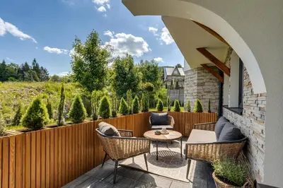 a patio with chairs and a table and a fence at BABIA GÓRA Dream Apart in Zawoja