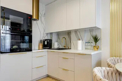 a kitchen with white cabinets and a black microwave at BABIA GÓRA Dream Apart in Zawoja
