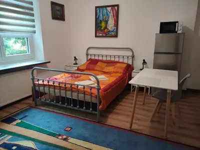 a bedroom with a bed and a table and a refrigerator at Apartment with kitchenette in Kraków