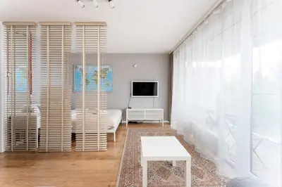 a white living room with a tv and a couch at Lindego Park Comfy Studio by BookingHost in Kraków