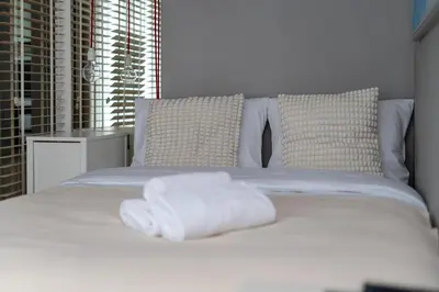 a white bed with two folded towels on it at Lindego Park Comfy Studio by BookingHost in Kraków