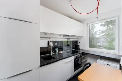 a kitchen with white cabinets and a window at Lindego Park Comfy Studio by BookingHost in Kraków