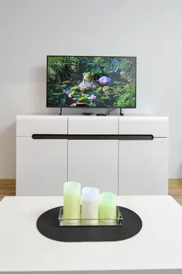 a white entertainment center with a tv and candles at JJ Apartment Zator Energylandia in Zator