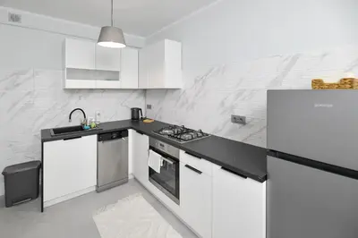 a kitchen with white cabinets and a black counter top at JJ Apartment Zator Energylandia in Zator