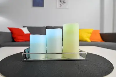 a candle holder with three white candles on a table at JJ Apartment Zator Energylandia in Zator