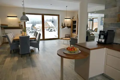 a kitchen and living room with a table with a bowl of fruit at Babie Zacisze in Zawoja