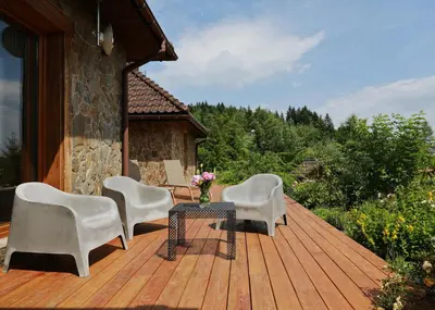 a wooden deck with chairs and a table and flowers at Babie Zacisze in Zawoja