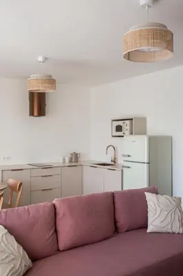a living room with a purple couch and a kitchen at Nad Jeziorem in Rożnów