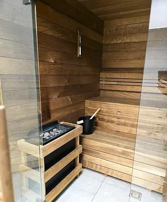 a sauna with wooden walls and a glass door at Royal Kątowa Apartment in Kraków