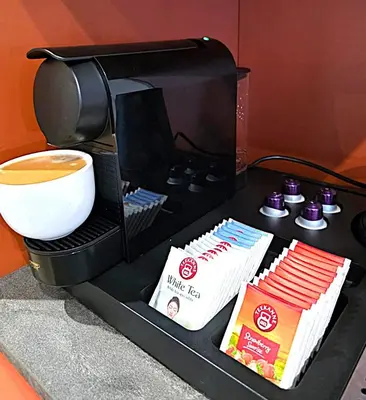 a coffee maker with a cup of coffee and books at Royal Kątowa Apartment in Kraków