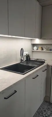 a kitchen with a black sink and white cabinets at Apartament Kraków Łobzów in Kraków