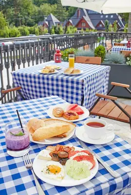 a blue and white checkered table with plates of breakfast foods at Domki Czarny Groń in Rzyki