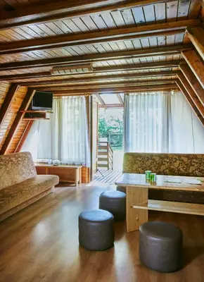 a living room with a couch and a table and stools at Domki Czarny Groń in Rzyki