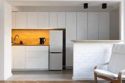 a kitchen with white cabinets and a white refrigerator at Studio Lublańska - przytulne, nowoczesne, w klimacie Krakowa in Kraków