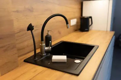 a kitchen counter with a sink with a soap dispenser at Studio Lublańska - przytulne, nowoczesne, w klimacie Krakowa in Kraków