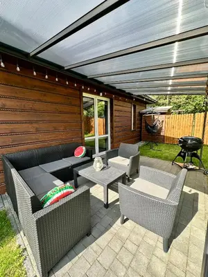 a patio with chairs and tables and a grill at Domek nad Jeziorem Siamoszyce in Siamoszyce